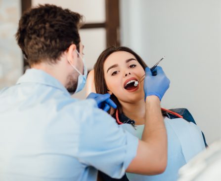 dentist-making-professional-teeth-cleaning-withb-cotton-female-young-patient-dental-office